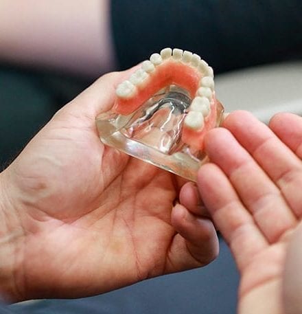 doctor holding prosthetic mouth with teeth